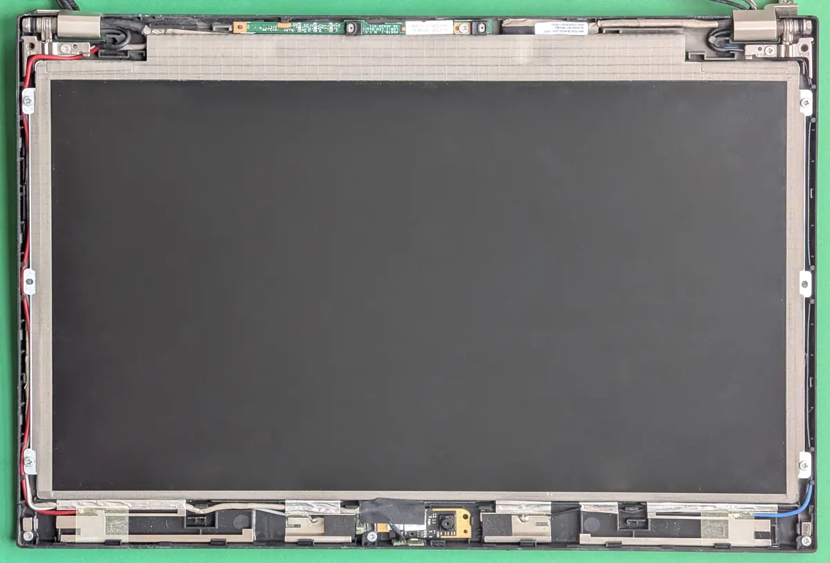 Disassembled laptop display lid showing the LCD panel and back cover